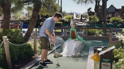 Man playing mini golf with owl watching
