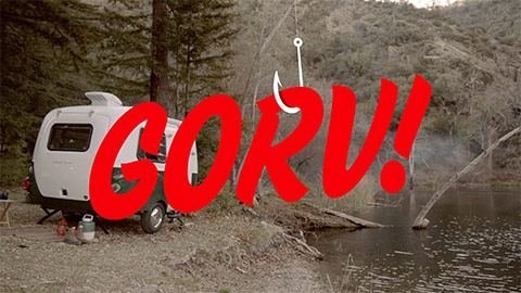 Small camper RV next to a wooded stream with GORV! superimposed on the image
