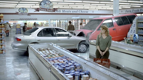 Woman in ice cream aisle of grocery store, with two cars that have collided head-on behind her
