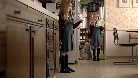 Two girls with homework standing in kitchen