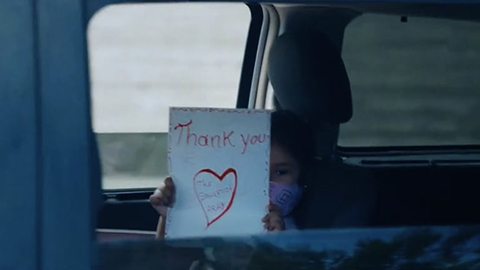 Child in car holding thank you sign