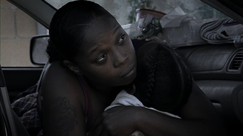 woman hugging a child in a car, surrounded by belongings