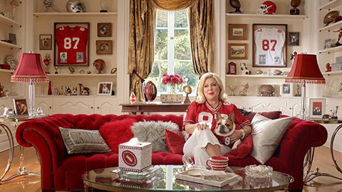 Woman sitting on couch in room decked out in football gear