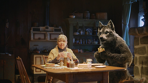 Wolf and woman eating sandwiches at a table