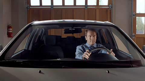 Man sitting in driver's seat of car with hands on the steering wheel