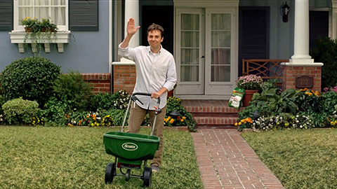 man fertilizing lawn and waving