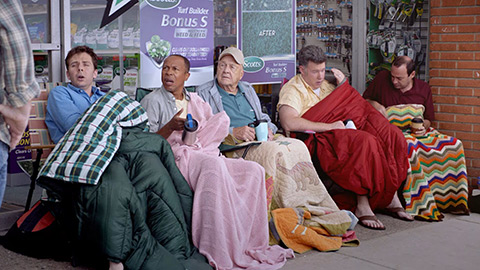 old people sitting in line with blankets outside